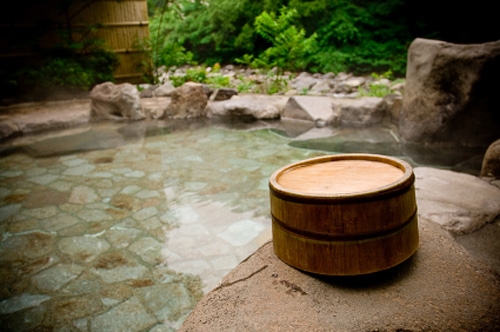 A wooden bucket by an outdoor Japanese hot spring bath in Hakone, Japan